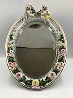 Full view of oval porcelain frame mirror with cherubs and floral details