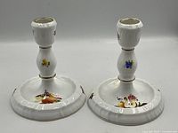 Front view of both candlesticks showing hand-painted fruit and gilt accents