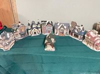 Front view of all eight ceramic village pieces lined up on table