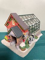 Front three-quarter view showing cottage entrance, greenhouse, bicycle and snow details