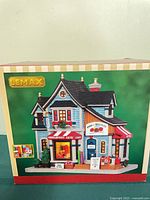 Front of boxed Lemax Pins & Needles lighted building