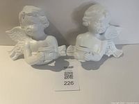 Front view of both white angel candle holder statues