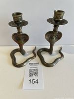 Front view of both brass snake candlesticks showing design and height reference