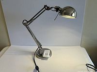 Full view of chrome articulated desk lamp on base
