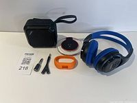 Group shot of speaker, headphones, Vivofit tracker, orange band and two audio adapters