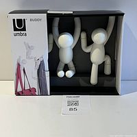Front view of Umbra Buddy hooks boxed set showing brand, product name and three white figure hooks inside.