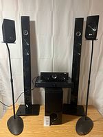 Front view of full LG surround sound system with towers, satellites on stands, center speaker, receiver, and subwoofer