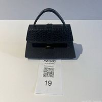 Full view of black purse-shaped Post-it dispenser