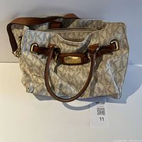 Front view of beige MK monogram satchel with brown leather handles and gold hardware