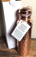 Full view of copper bottle beside original box