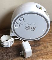 Front view of BlissLights Sky Lite projector with controls and adapter
