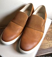 Top view of both sneakers showing brown uppers and ribbed elastic panel