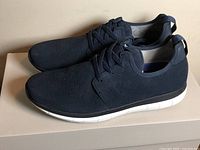 Side view of both navy shoes on box highlighting perforated uppers and white soles