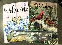 Two garden flags and packaged metal pole displayed on countertop