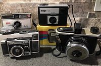 Group shot of four vintage cameras: Kodak Instamatic 14, Kodak Instamatic X-45, Kodak 620 model, and Mupi S4 with box