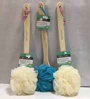 Front view of three Ecotools Ecopouf bath brushes showing bamboo handles, mesh poufs and retail tags
