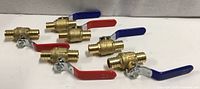 All six brass PEX ball valves laid out showing both handle colors and barb ends