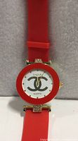 Front view of Chanel watch showing red bezel, white dial with logo, red silicone strap
