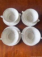 Overhead view of four soup dishes on saucers