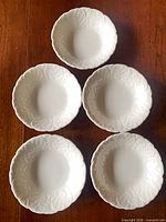 Five white leaf-pattern bowls arranged on table