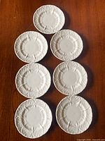 Full set of seven white leaf-molded plates on table