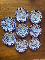Top view of all eight matching Imari plates on wooden surface