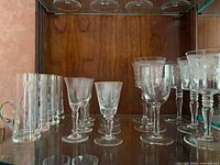 Cabinet shelf showing tall slender glasses, conical sherry glasses and etched goblets
