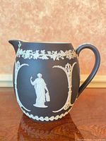 front view of black jasperware pitcher showing classical figure and ivy band