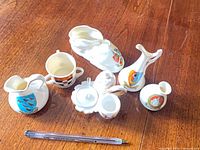 group shot of six Carlton China miniature crested pieces with pen for scale