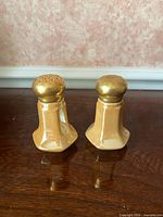 Front view of both porcelain shakers showing peach glaze and gold tops