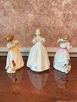 Front view of three Royal Doulton girl figurines on tabletop
