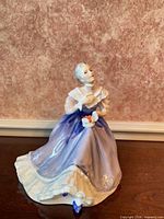 Front view of Royal Doulton "Happy Anniversary" figurine showing seated woman, gift box, detached blue lid