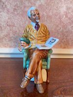 Front view of figurine showing man, boy, book and chair