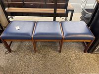 Front angled view showing full bench with three blue vinyl seats on wood frame