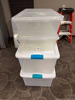 Stack of four clear plastic storage bins with lids and latches