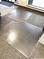Two clear vinyl chair mats on carpeted floor