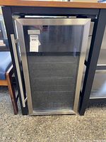 Frontal view of stainless steel glass-door wine fridge under counter