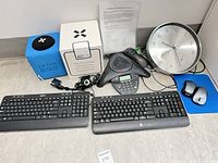 Lot overview showing conference phone, Catchbox mic, keyboards, mice, clock, cables