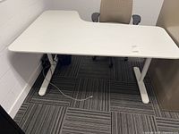Angled view of desk with chair, showing legs and mesh tray