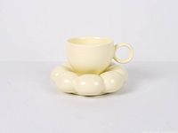 Front view of yellow ceramic cup on cloud saucer