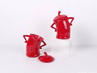 Both red resin canisters, one upright and one tilted, one lid removed
