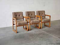 Front view of three matching oak armchairs with wool upholstery