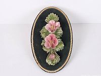 Full front view of oval plaque with porcelain flowers