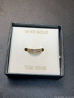 Toe ring in presentation box showing gold color and stones