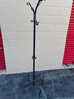 Full view of tall black metal coat rack against wall