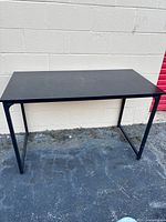 Full view of black rectangular computer desk against wall