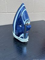 Profile view of blue and white Rowenta steam iron with cord wrapped around base