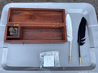 Entire set laid out: wooden box open, two feather pens, ink powder packet