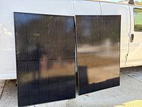 Front view of two black solar panels leaning against van