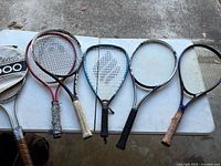 Five racquets and Wilson cover on folding table